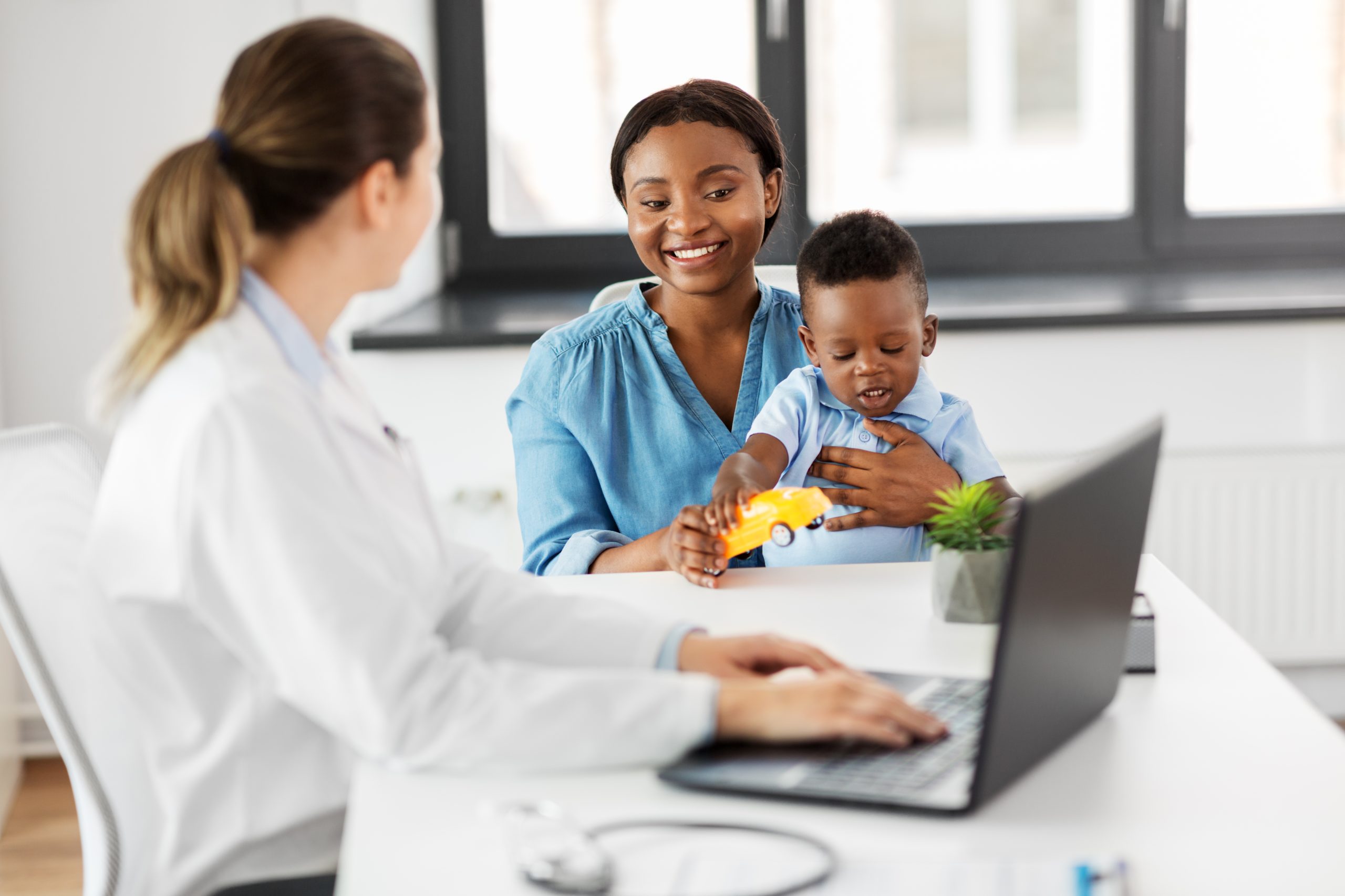 happy mother with baby son and doctor at clinic